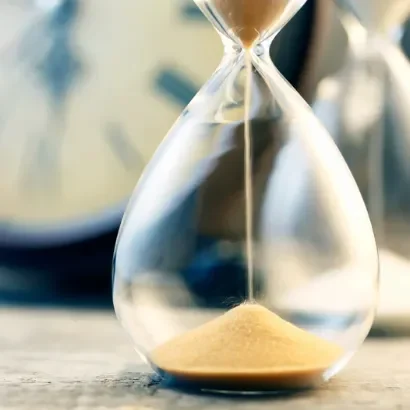Gain de temps Sablier en verre transparent avec du sable doré, arrière-plan flou de montres.