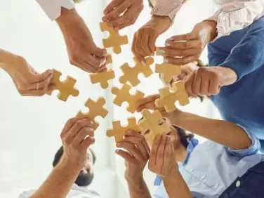 Un réseau Des mains réunies tenant des pièces de puzzle en bois, formant un cercle.