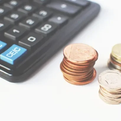 Budget maîtrisé Une calculatrice avec des pièces de monnaie empilées à côté.