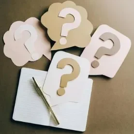 Des solutions Quatre bulles de dialogue avec des points d'interrogation sur un carnet et un stylo.